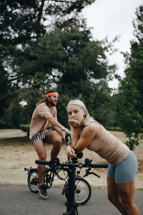 Free Two young adults on bicycles, enjoying a leisurely outdoor ride in a serene park setting. Stock Photo