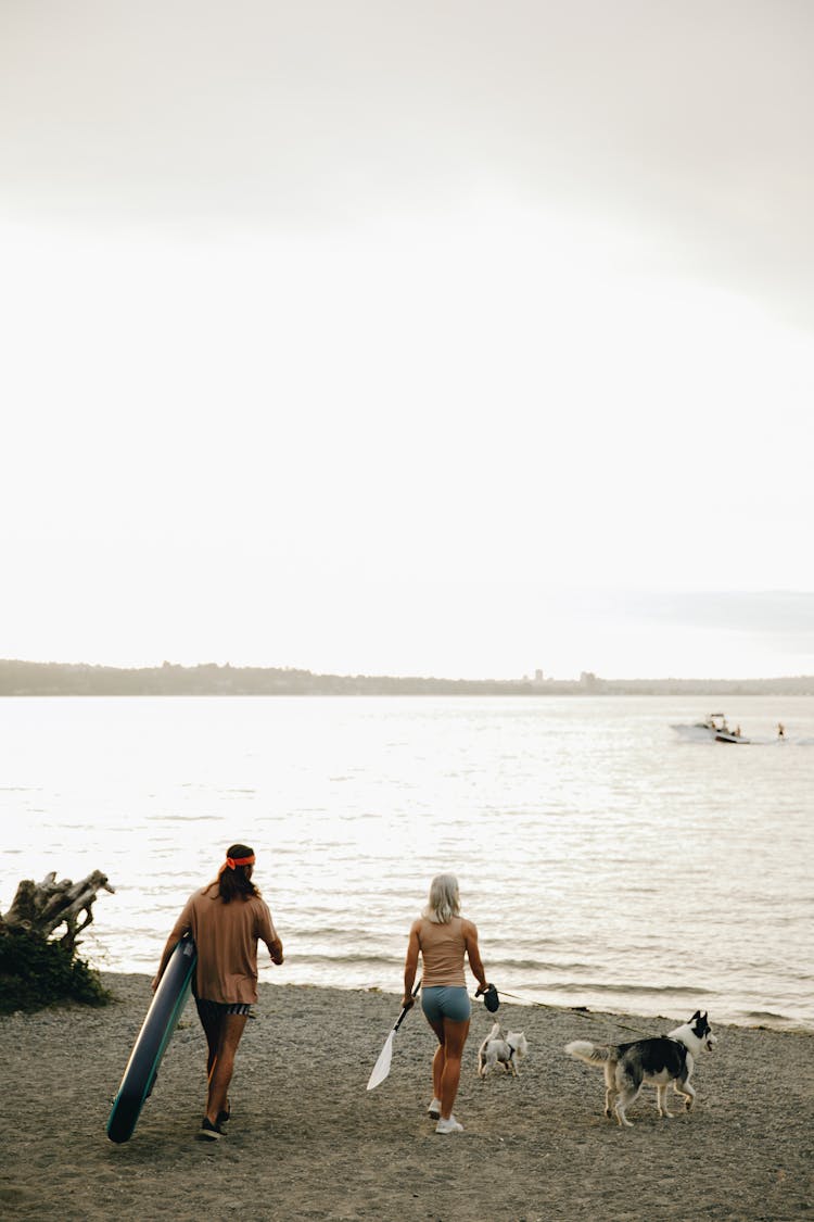 A Couple In The Beach With Their Dogs