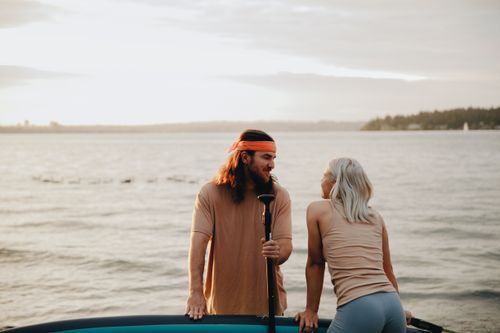 Free Couple enjoying a paddleboarding adventure during sunset on a serene lake. Stock Photo