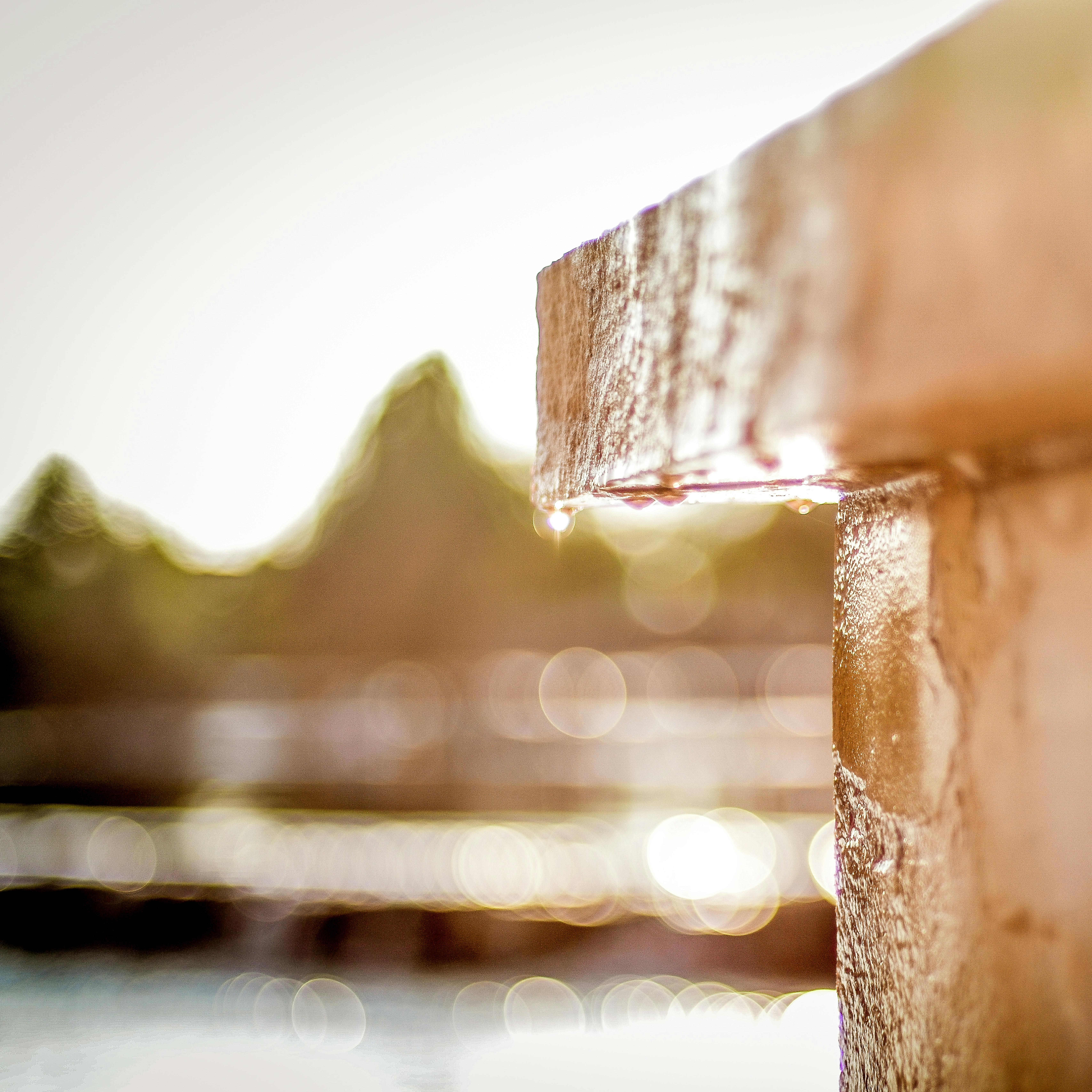 Bokeh effect with water droplets shimmering on a sunlit stone structure.