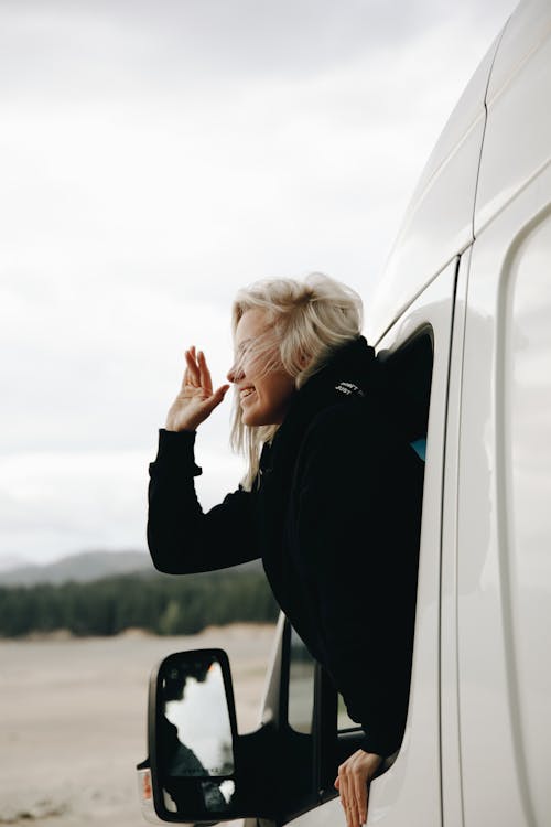 Free A Blonde-Haired Woman inside a Van Waving Her Hand Stock Photo