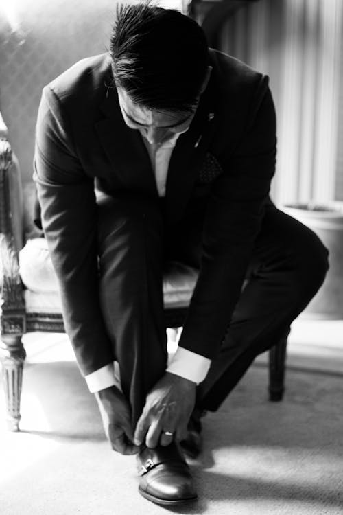 A Man in a Suit Tying His Shoelace 