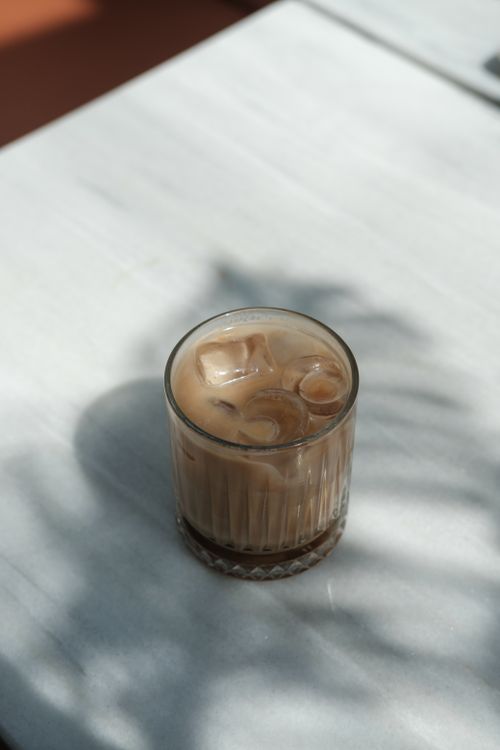 Free Cool iced coffee in a glass on a marble table with soft natural shadows. Stock Photo