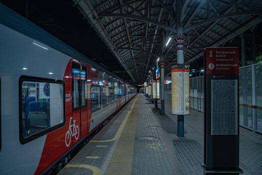 Wide-angle view of an urban train station at night with empty platform.
