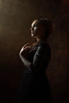 Side view of a woman in a black dress, in a dim, atmospheric setting.