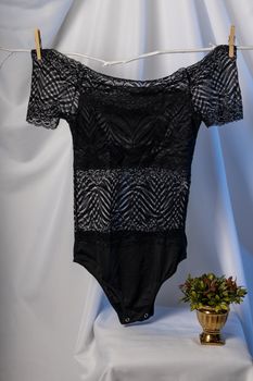 Elegant black lace bodysuit with intricate patterns, highlighted against a white background for a stylish fashion showcase.