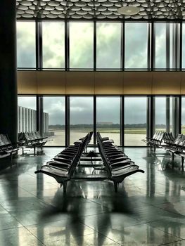 A modern airport terminal in Langenhagen, Germany, offering a spacious waiting area with rows of empty chairs and large windows.