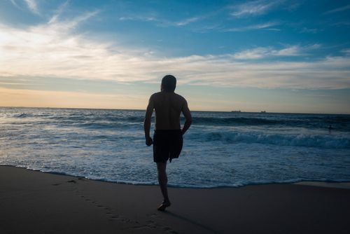 Free Silhouette of a man walking towards the sea during sunset, capturing tranquility and escape. Stock Photo