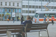 城市的长凳上坐着一位老人，电车经过，捕捉了城市生活的瞬间