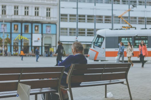 城市的长凳上坐着一位老人，电车经过，捕捉了城市生活的瞬间