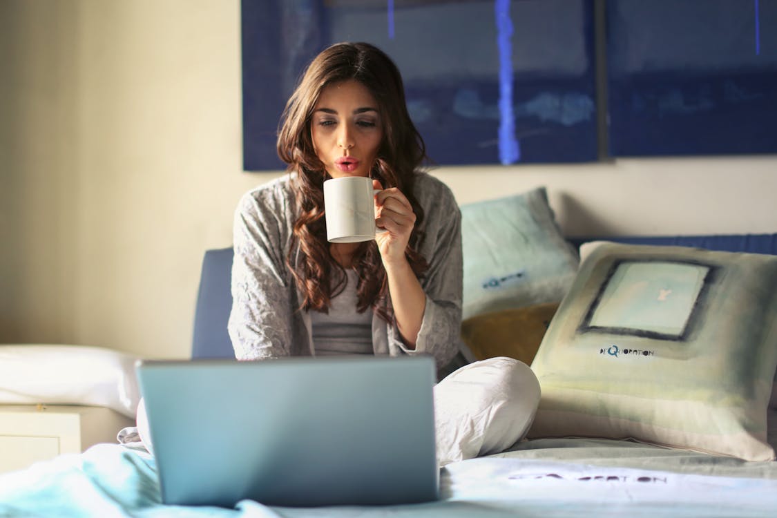 Vrouw In Grijze Jas Zit Op Bed Gebruikt Grijze Laptop