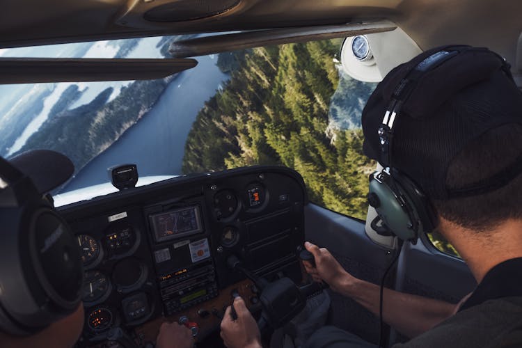 Pilots In A Plane Flying Over A River And Trees