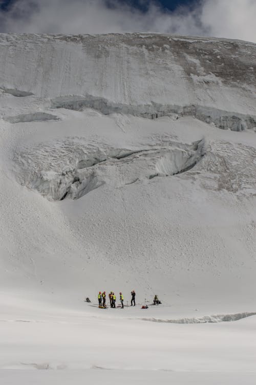 Skiers Standing at the Bottom of a Snow Covered Mountain