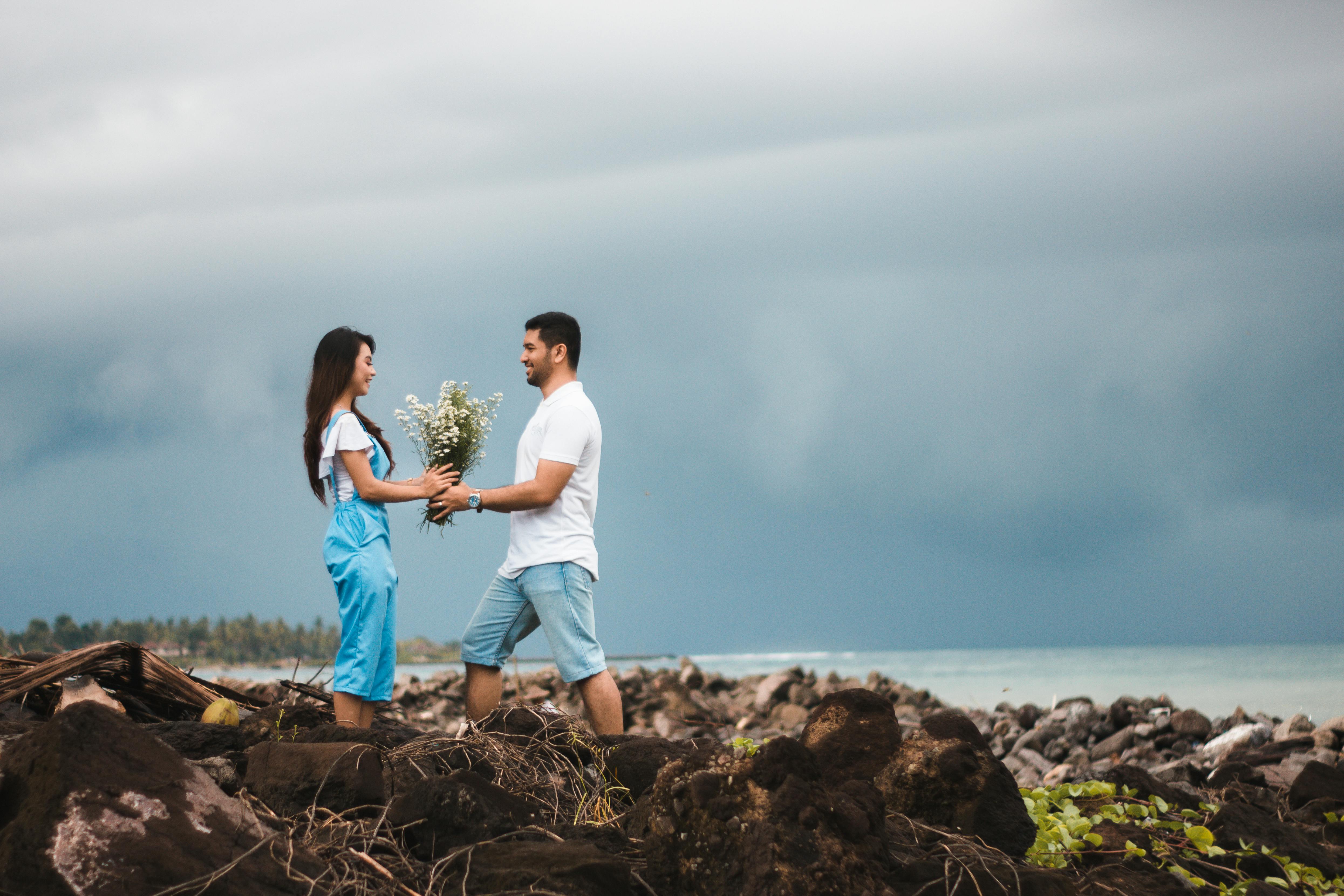 photo of man giving flowers to woman