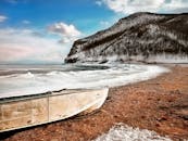 White Boat on Seashore Near Mountain Under White and Blue Sky