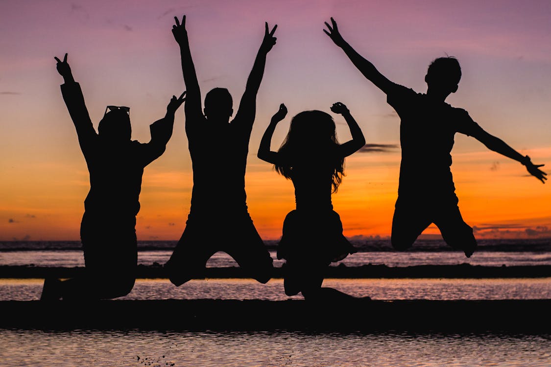 Silhouettes of people jumping at the beach. 