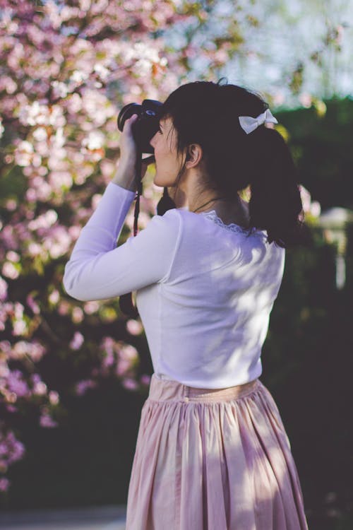 Woman in Pink Skirt Holding Camera Try to Picture the Tree