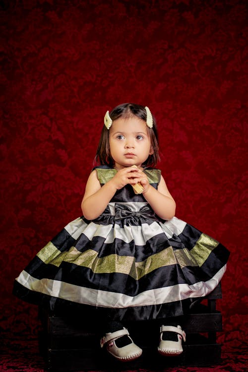 A Cute Girl in Striped Dress Sitting with Hair Clips on Her Head