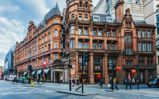 Vibrant street scene showcasing historic architecture with pedestrians and traffic in a lively city center.