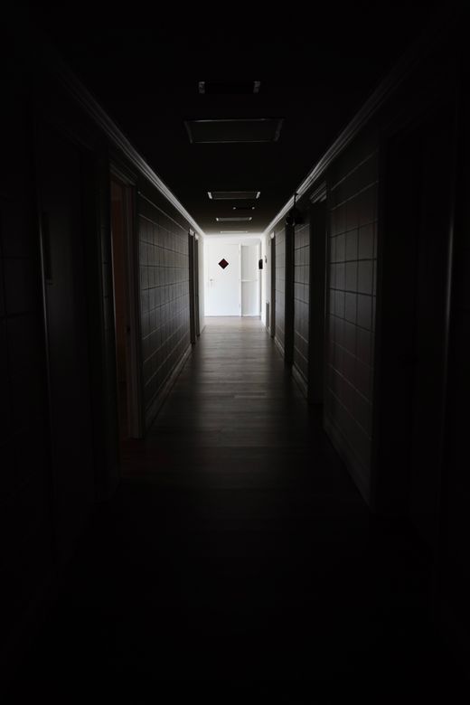 Long dim corridor opening onto a lit doorway — photo by Julio Agreda on Pexels