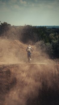 Thrilling off-road motorcycle ride on a dusty dirt track under clear skies.