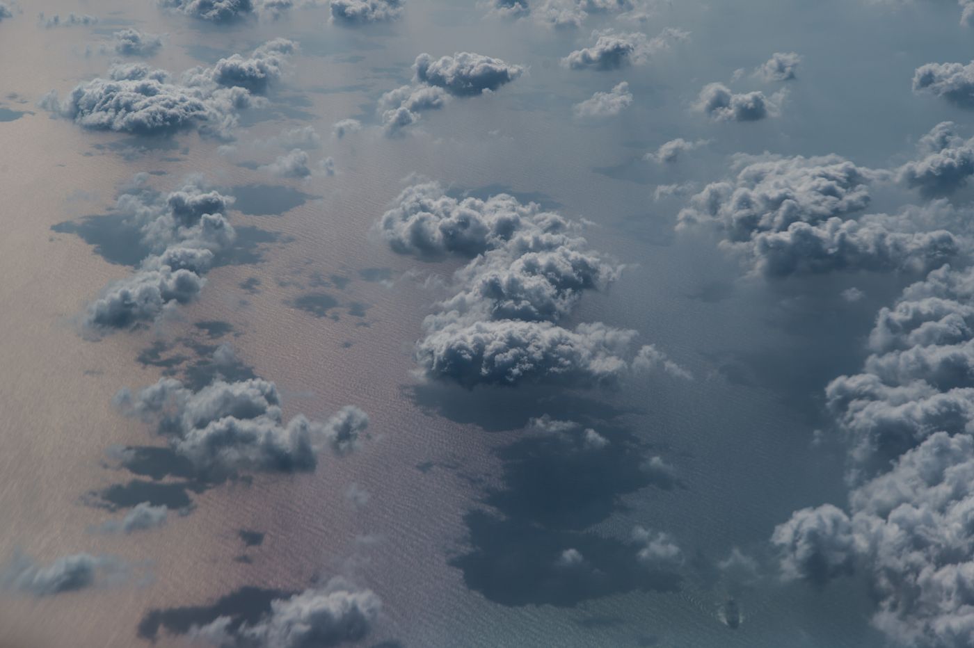 Aerial view of scattered cloud cover casting shadows on open ocean — photo by eddie chuachoonhui on Pexels