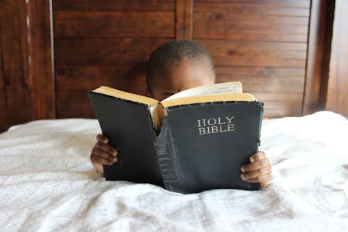 Free Photo of Child Reading Holy Bible Stock Photo