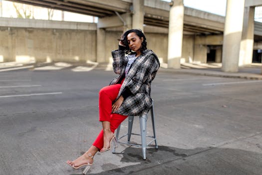 一位穿着红裤子和格子外套的时尚女子在城市立交桥下摆姿势