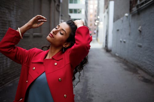 Woman in Red Coat Between Gray Concrete Walls