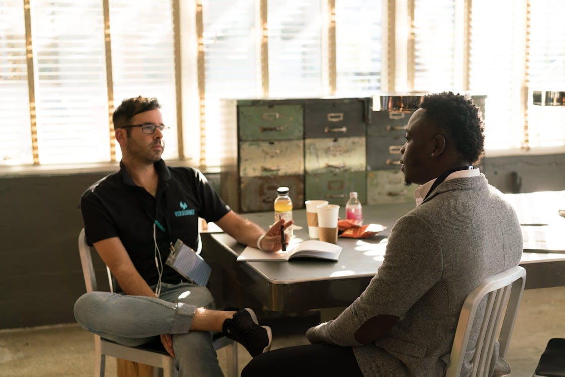 Free Man Wearing Black Polo Shirt and Gray Pants Sitting on White Chair Stock Photo