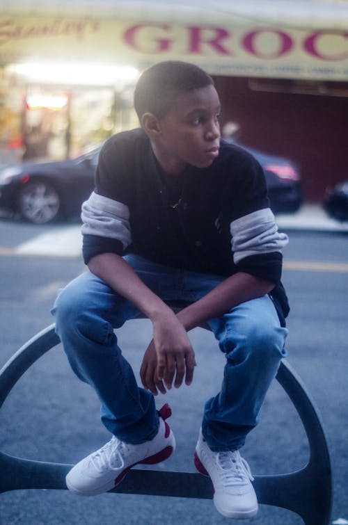 Free Sitting Boy Wearing Black and White Long-sleeved Shirt and Blue Denim Jeans Stock Photo