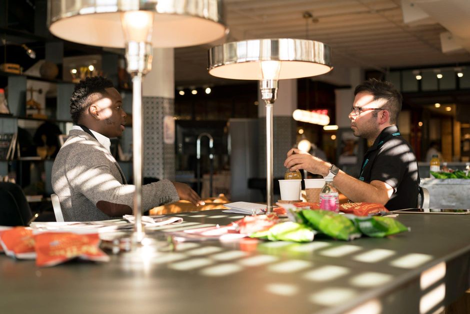 Two men engaged in discussion around a table in a modern office environment.