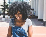 白天，一名卷发年轻女子在城市中微笑