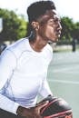 Man in White Crew-neck Long-sleeved Shirt Holding Black and Red Basketball