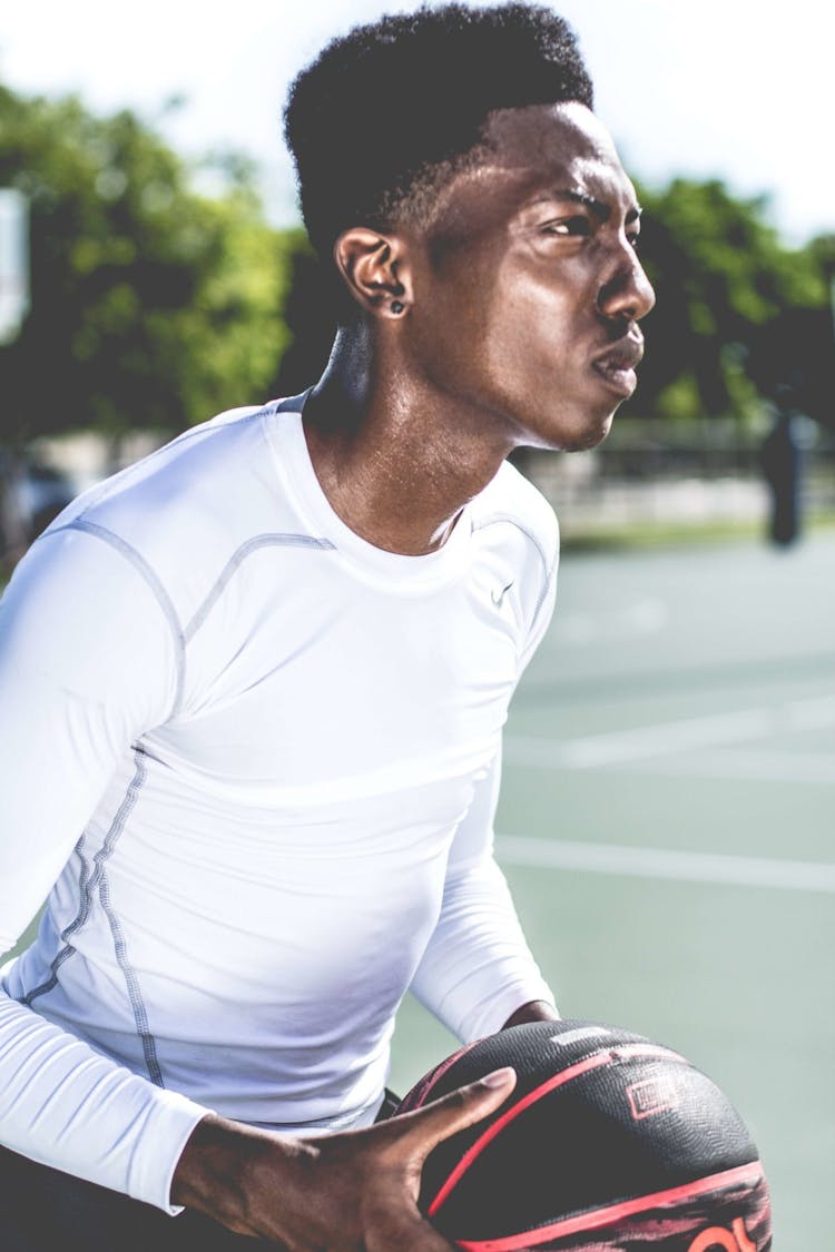 Man In White Crew-neck Long-sleeved Shirt Holding Black And Red Basketball