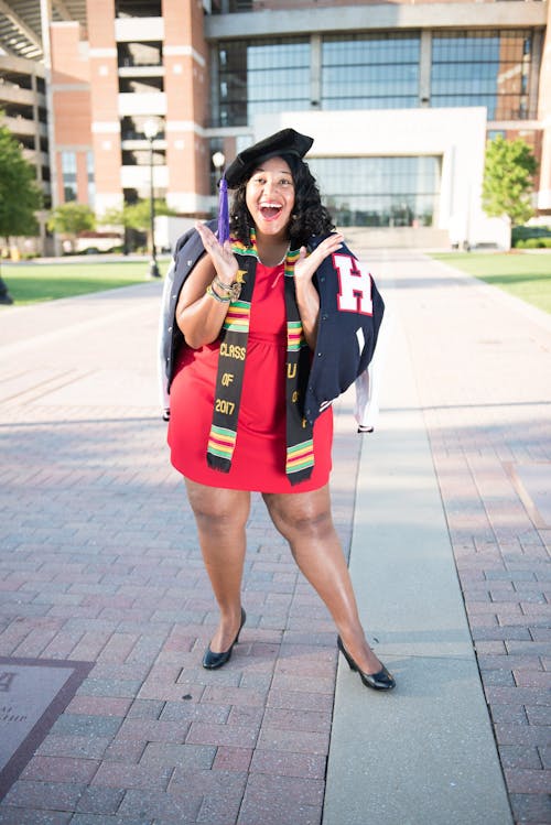 Woman Wearing Red Dress and Black Cap Taking Photo Near Building