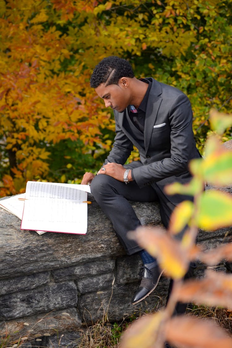 Man Wearing Black Suit Reading Book