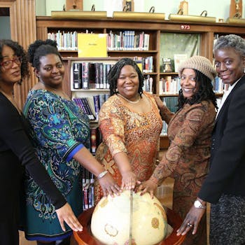 五名女性聚集在图书馆，象征着团结与教育