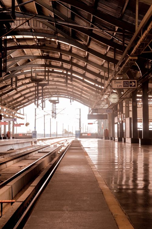 Free A serene empty train station platform with reflective surfaces at sunrise, highlighting transportation and travel. Stock Photo
