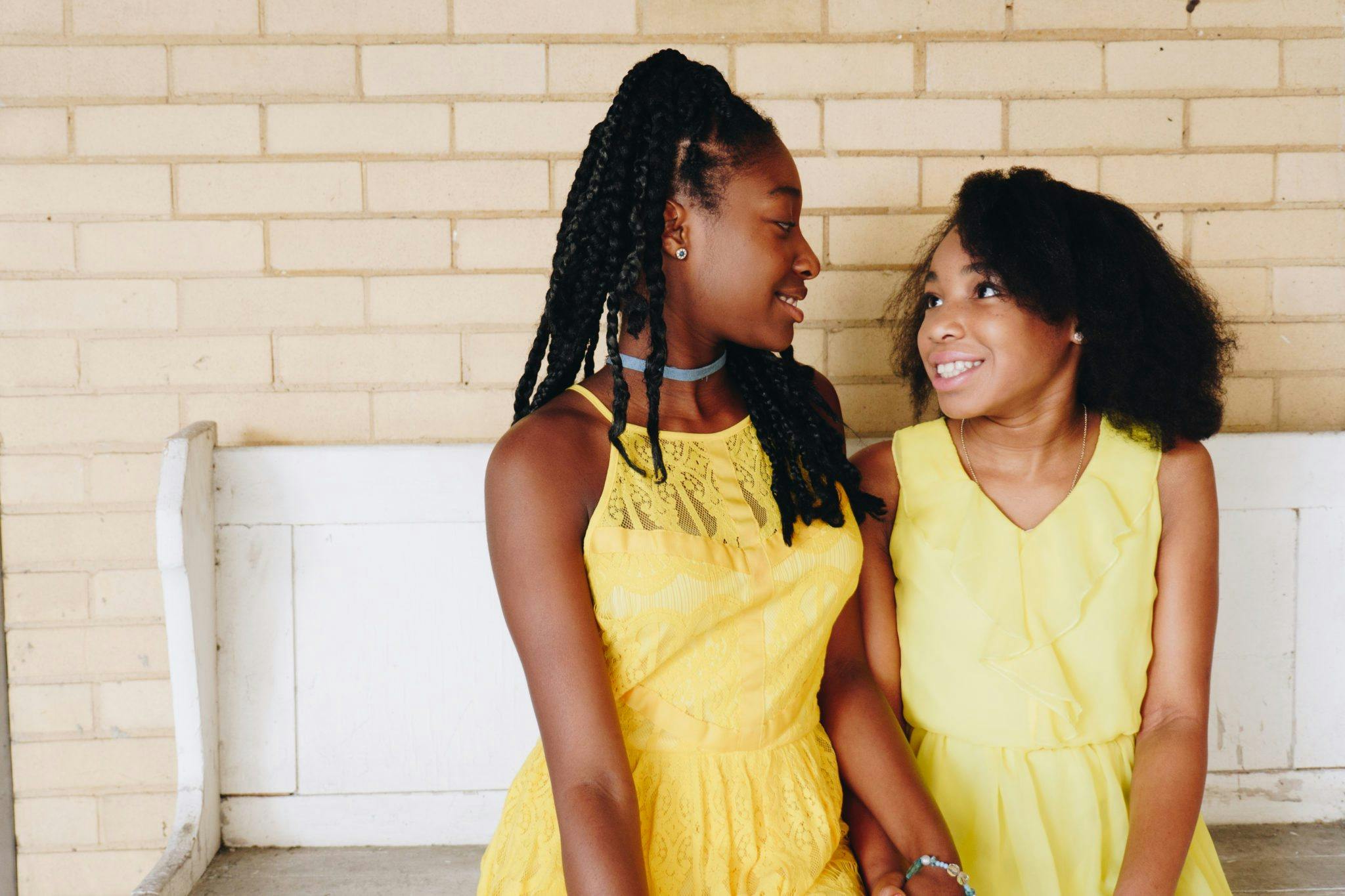 two girls wearing yellow sleeveless dresses