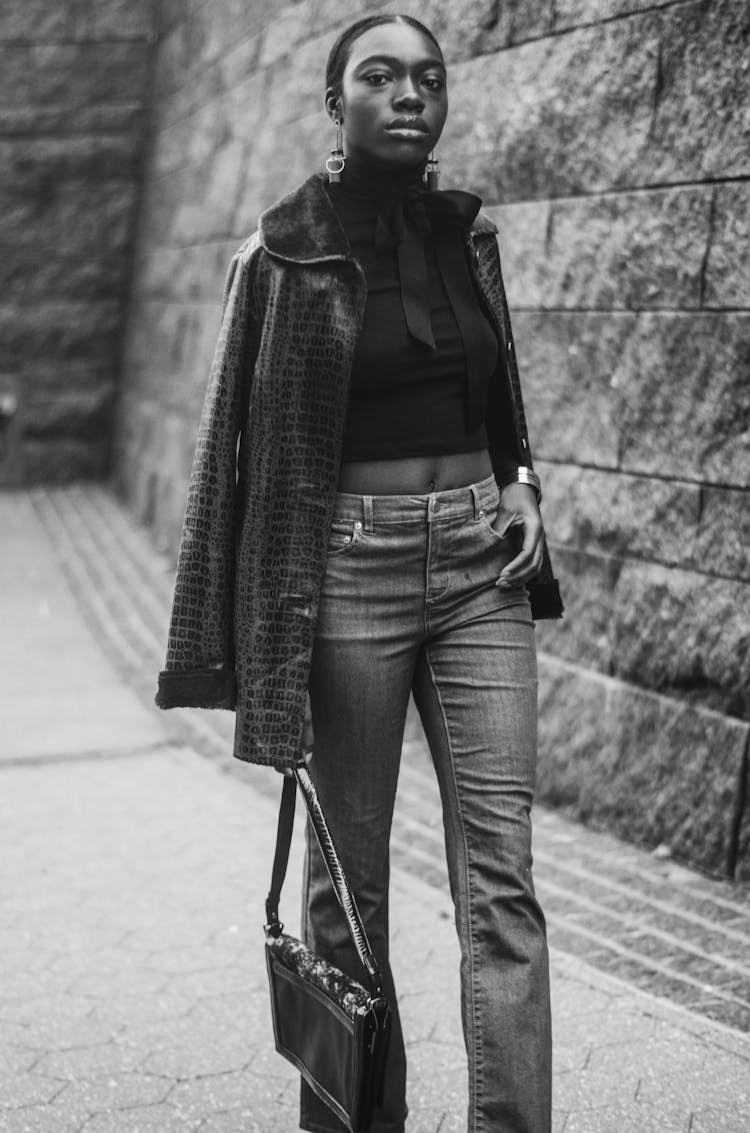 Woman In Jacket, Crop Top, And Pants Holding Bag