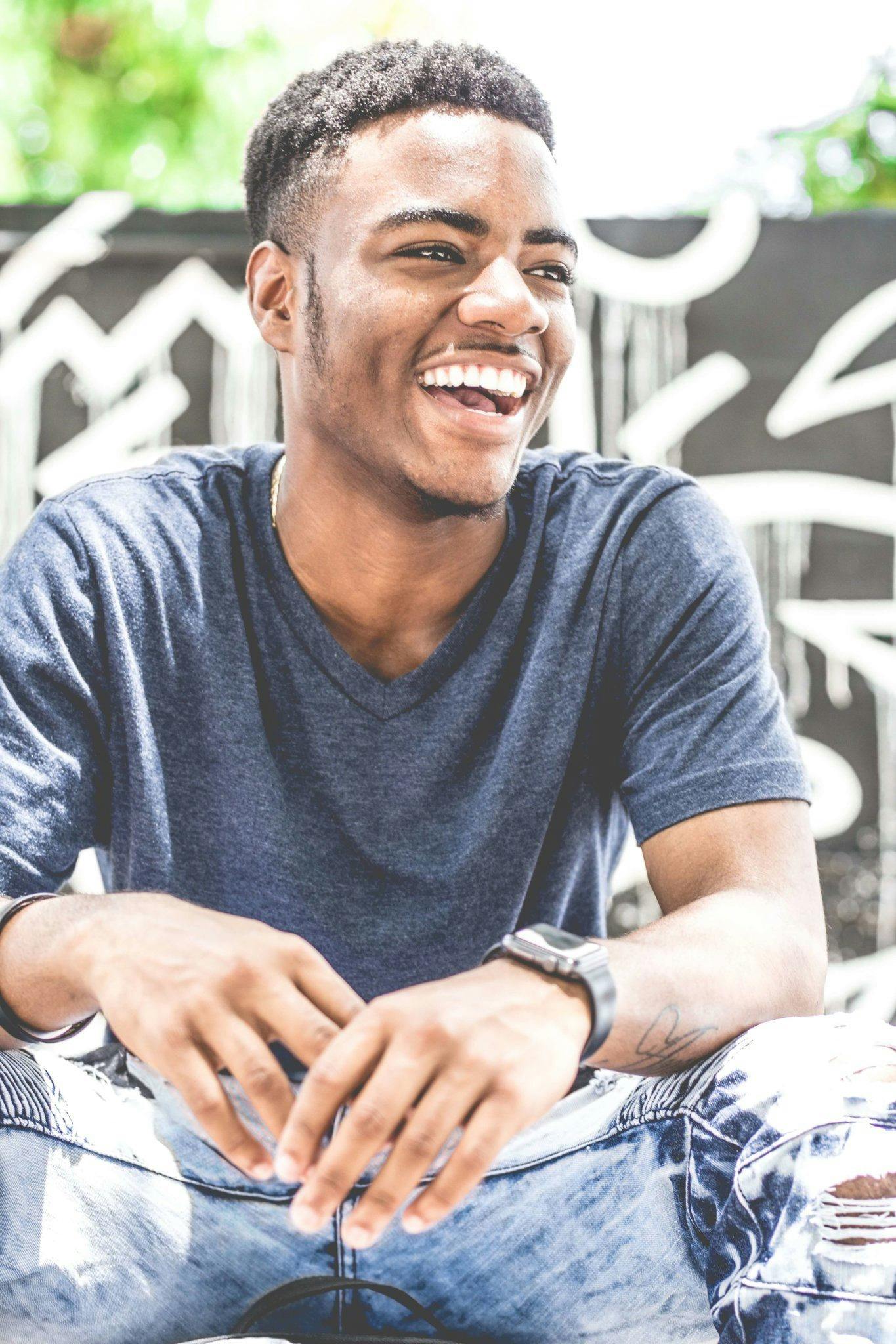 Lachender Mann in grauem T-Shirt mit V-Ausschnitt. | Quelle: Pexels