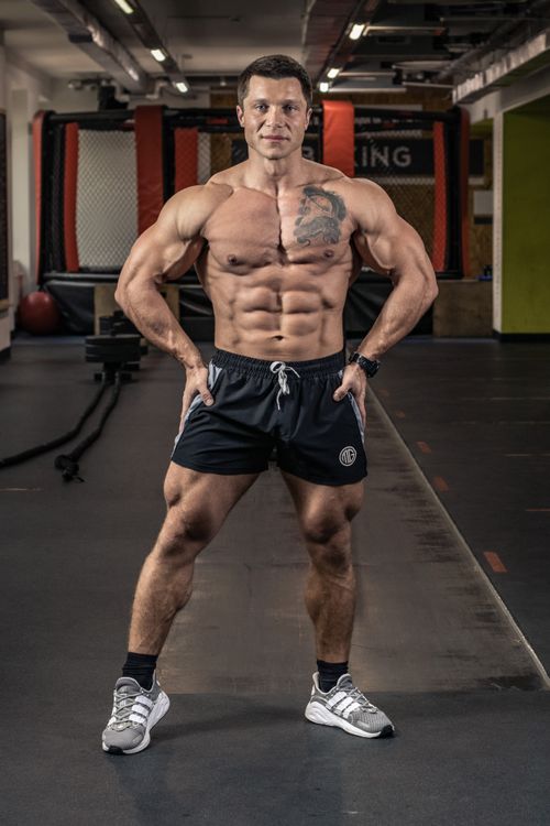 Free Muscular man with tattoos posing confidently in an indoor gym. Stock Photo