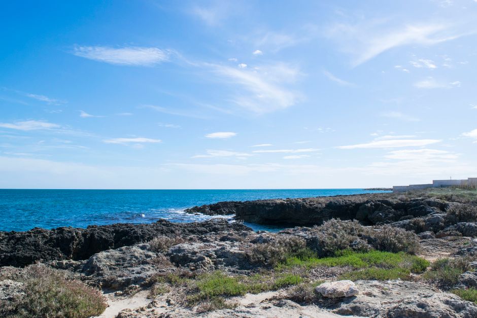 Tranquil coastal view featuring a rocky shoreline under a clear blue sky.