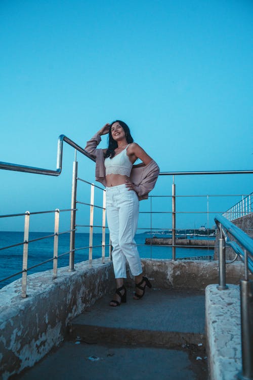 Woman in Bralette and Pants Posing Near Metal Railings 