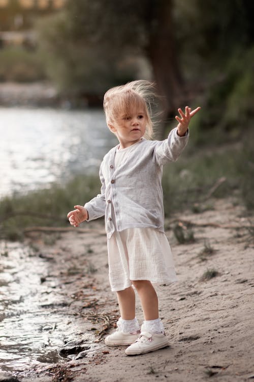 Photo of a Cute Kid Standing Near a Body of Water