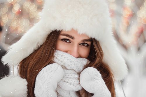 Free Close-up portrait of a young woman warmly dressed in winter clothes, with a snowy and bokeh background. Stock Photo
