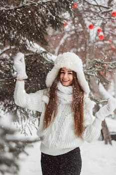 Happy woman in winter clothing enjoying a snowy day outdoors among pine trees.