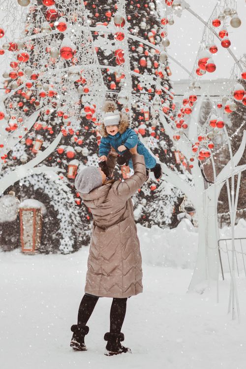 Free A joyful moment between mother and child in snow with festive decorations. Stock Photo