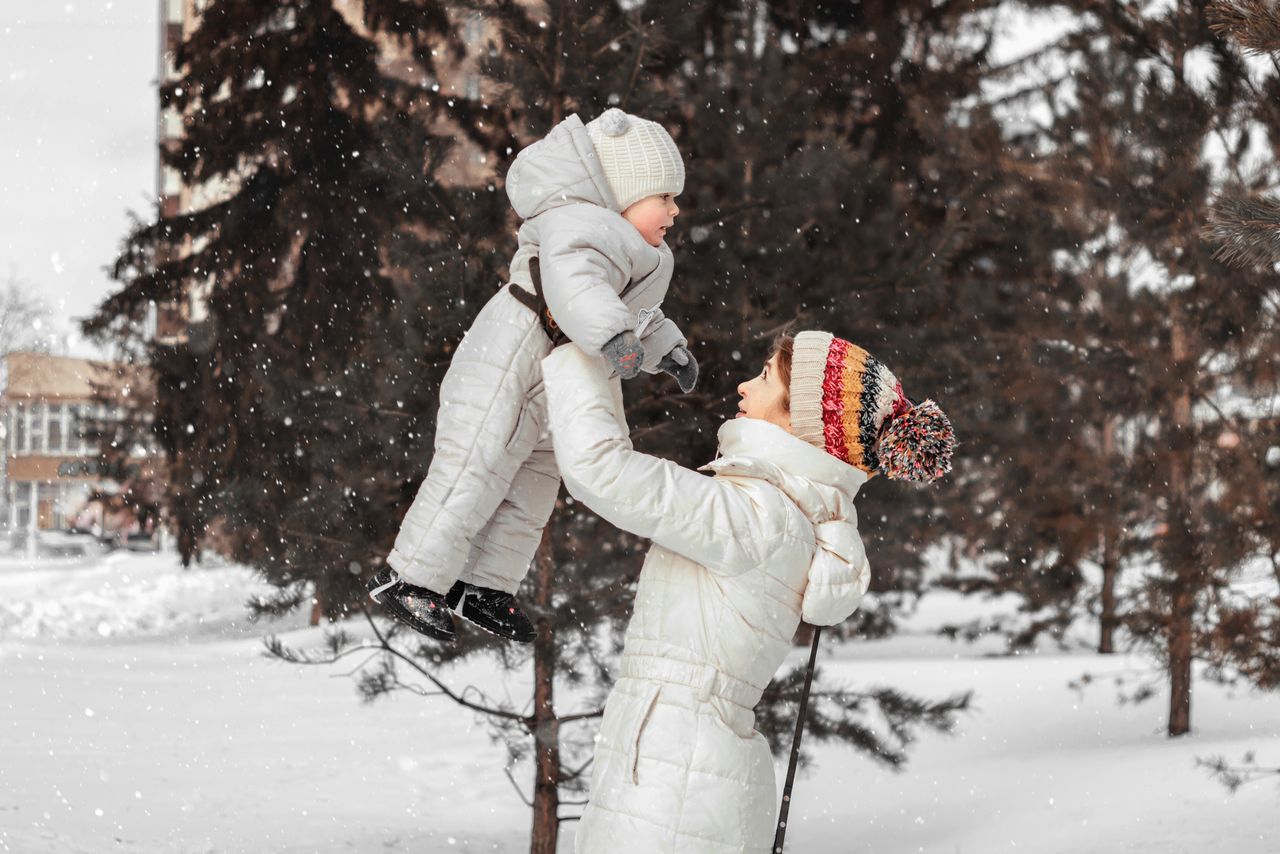 A parent lifting a bundled-up child outdoors in the snow — photo by Анастасия Триббиани on Pexels